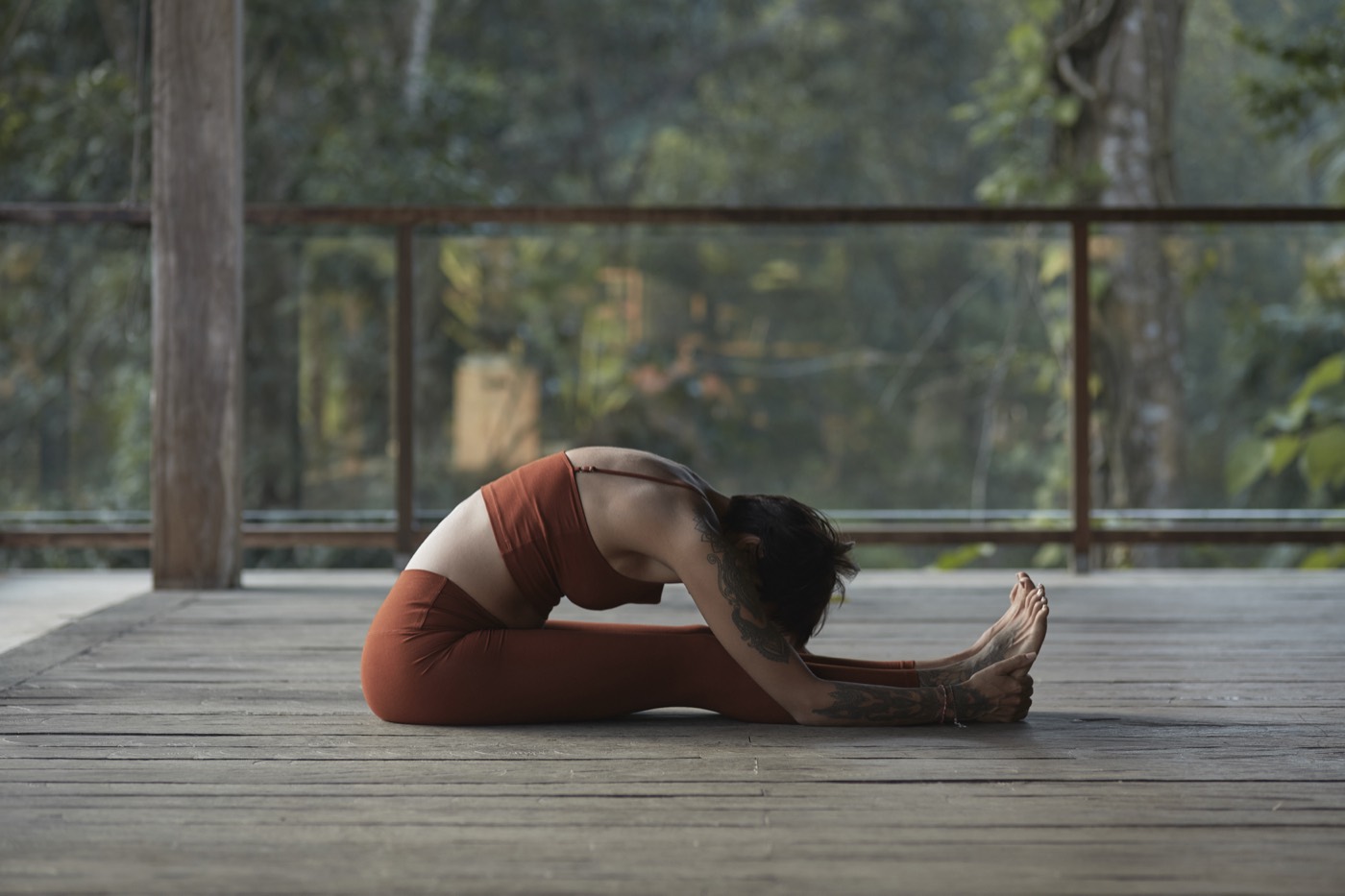 A student in a seated forward fold on a jungle deck